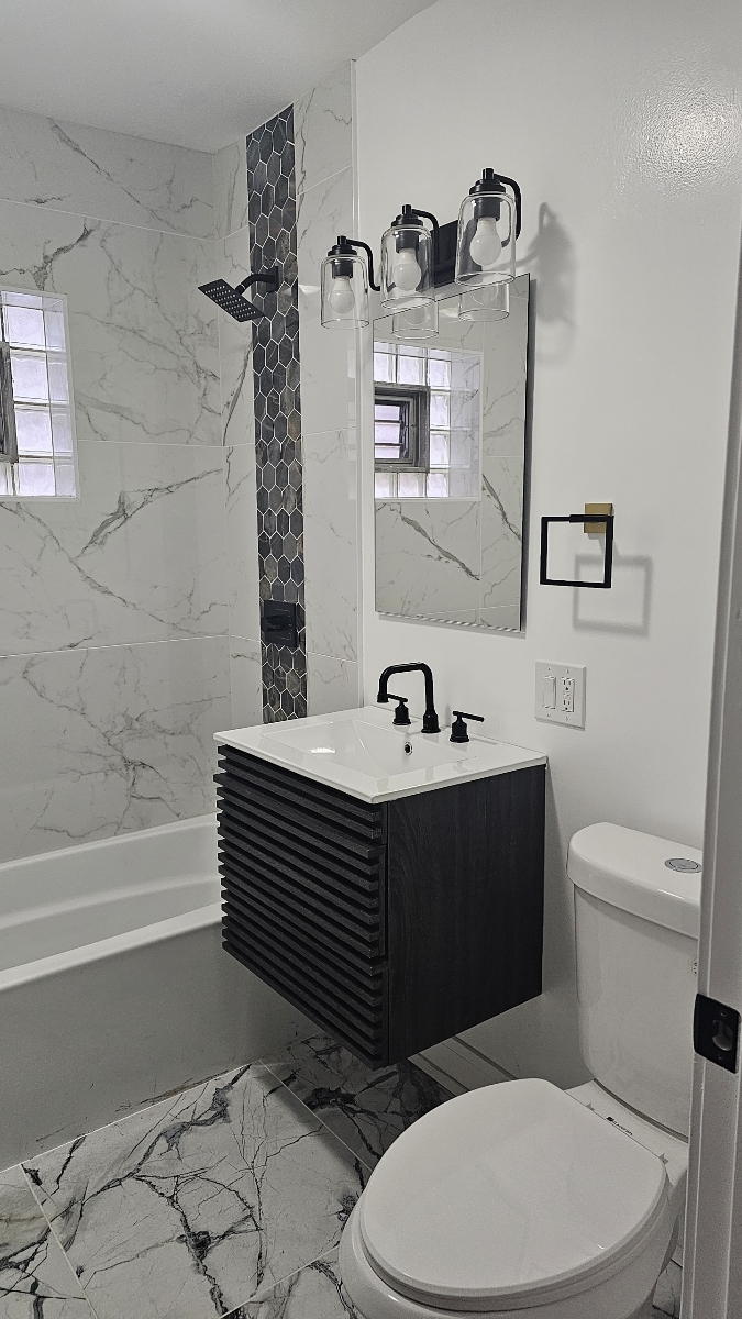 Completed black and white marble bathroom remodel with floating vanity and matte black fixtures