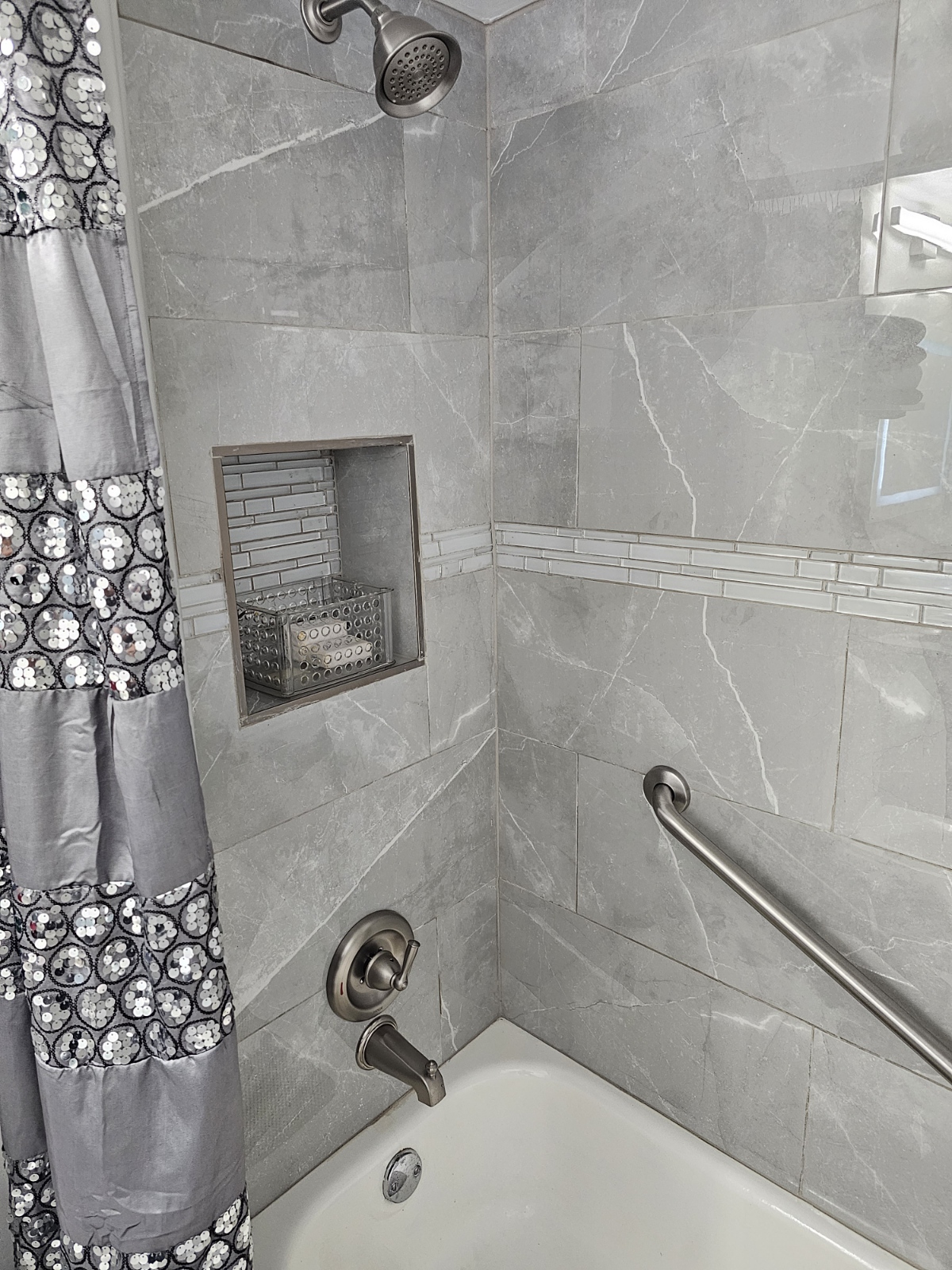 Gray marble tub surround with built-in niche and brushed nickel fixtures