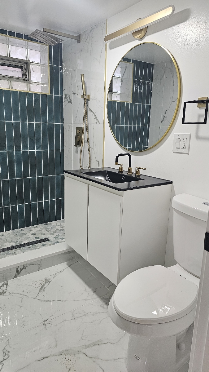 Luxury bathroom with teal subway tile shower, gold fixtures, and round mirror