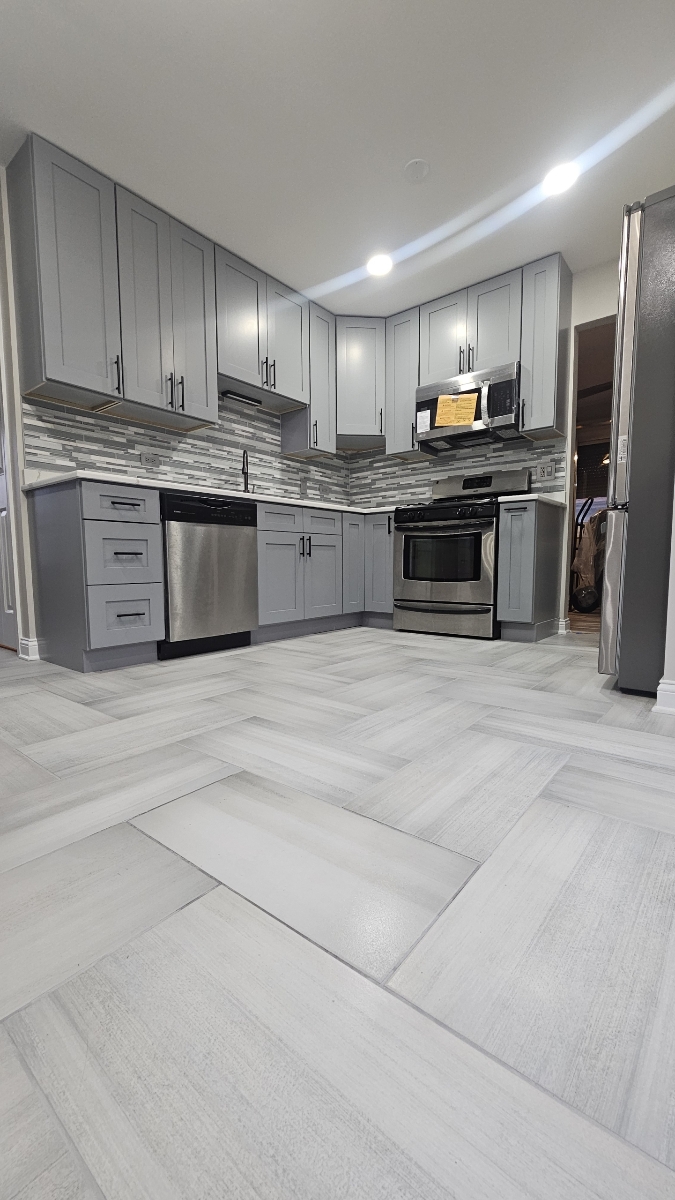 Gray shaker kitchen remodel with herringbone tile floor and stainless appliances