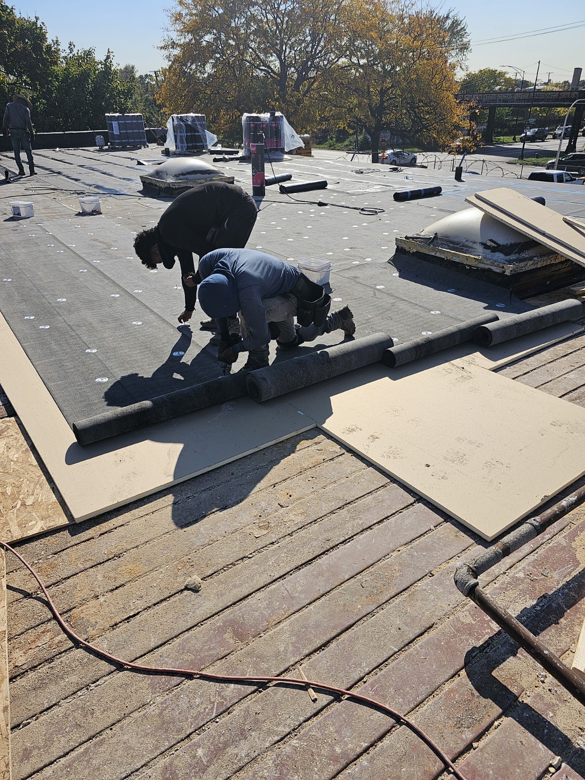 Workers installing modified bitumen membrane on a Chicago flat roof